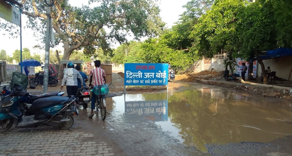 Neglected Delhi Jal Board repair site with hazardous mud and signage.